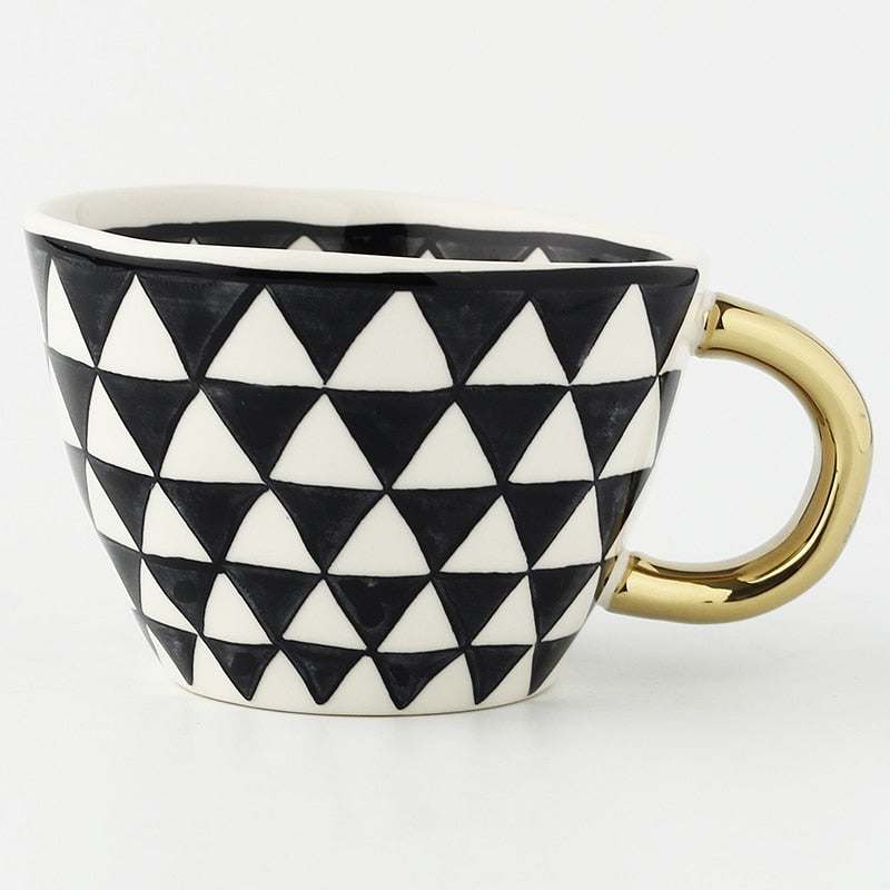 Tasse mit abstraktem geometrischem Muster und Goldhenkel