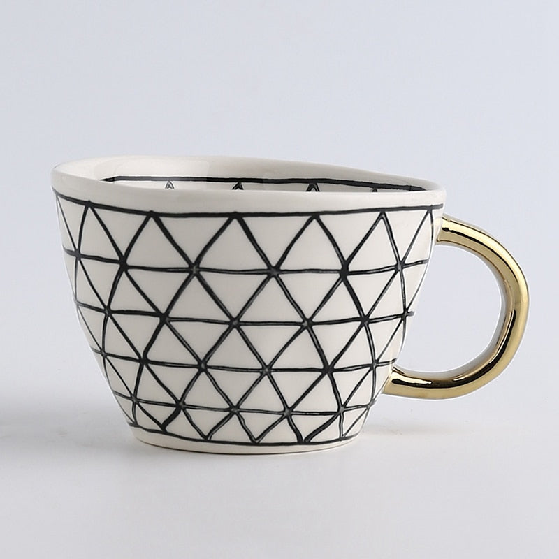 Tasse mit abstraktem geometrischem Muster und Goldhenkel