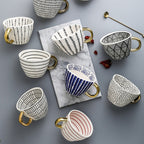 Tasse mit abstraktem geometrischem Muster und Goldhenkel