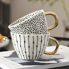 Tasse mit abstraktem geometrischem Muster und Goldhenkel