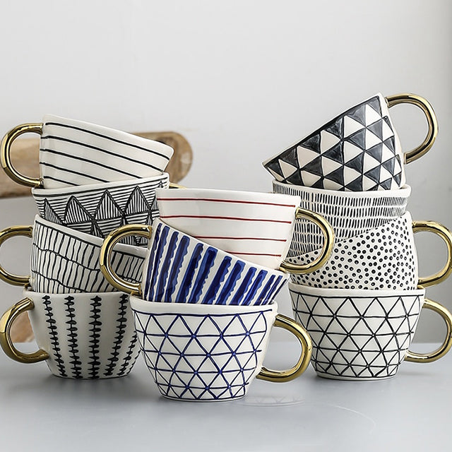 Tasse mit abstraktem geometrischem Muster und Goldhenkel